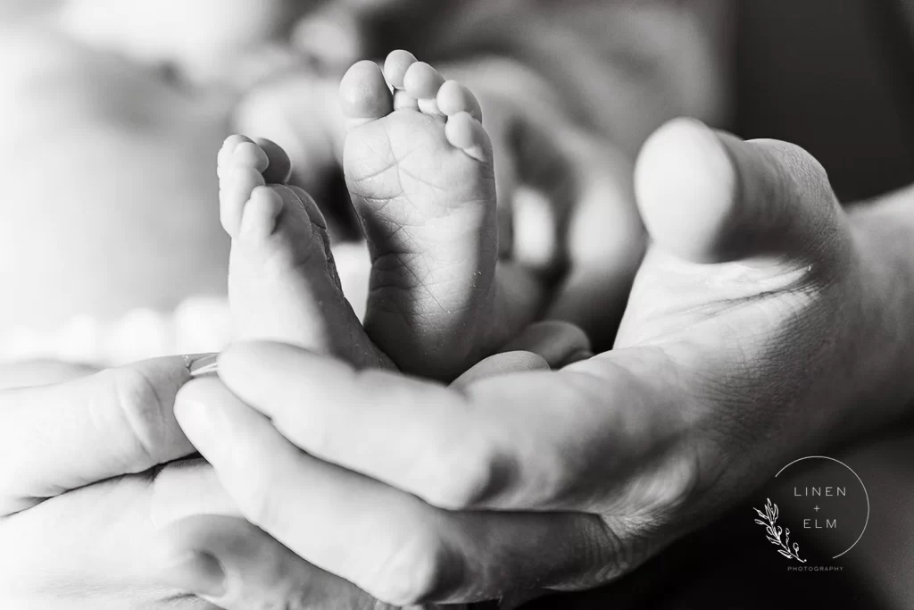 Tiny newborn feet held by dad black and white image Cincinnati Ohio