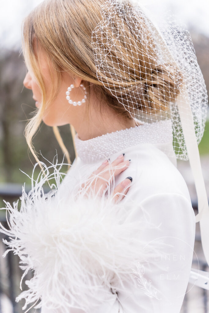Bride with feather accents on dress with net headpiece