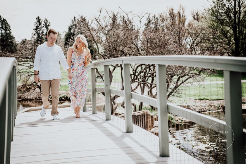 Couple laughing and walking across bridge engagement photography