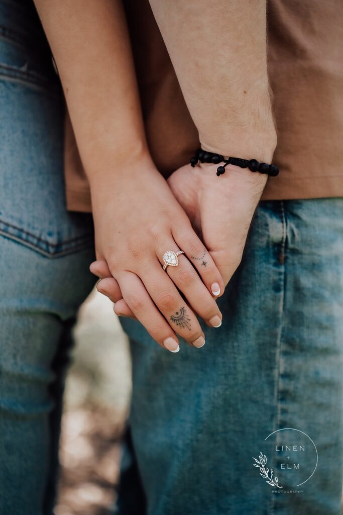 Couple holding hands featuring engagement ring