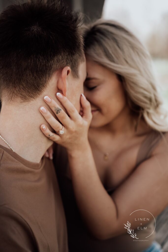 Over The Shoulder Moody Shot Of Couple Embracing Featuring Engagement Ring