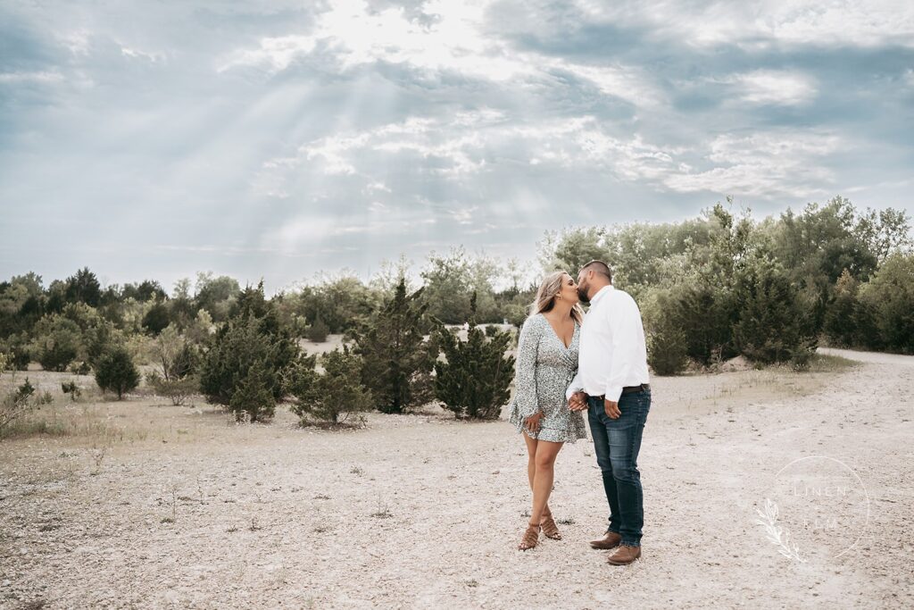 Sun rays shining down on engaged couple kissing in Ohio park, Bright Rustic Engagement Session Dayton Ohio