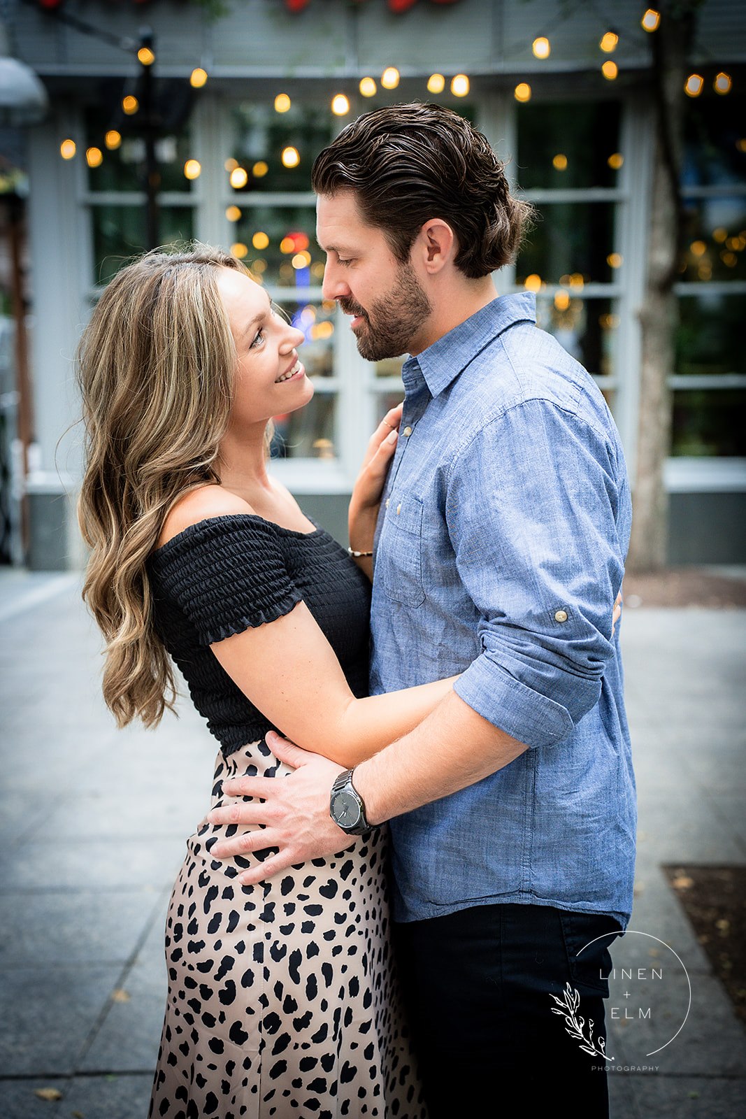 Couple posing downtown Cincinnati with twinkling lights in background