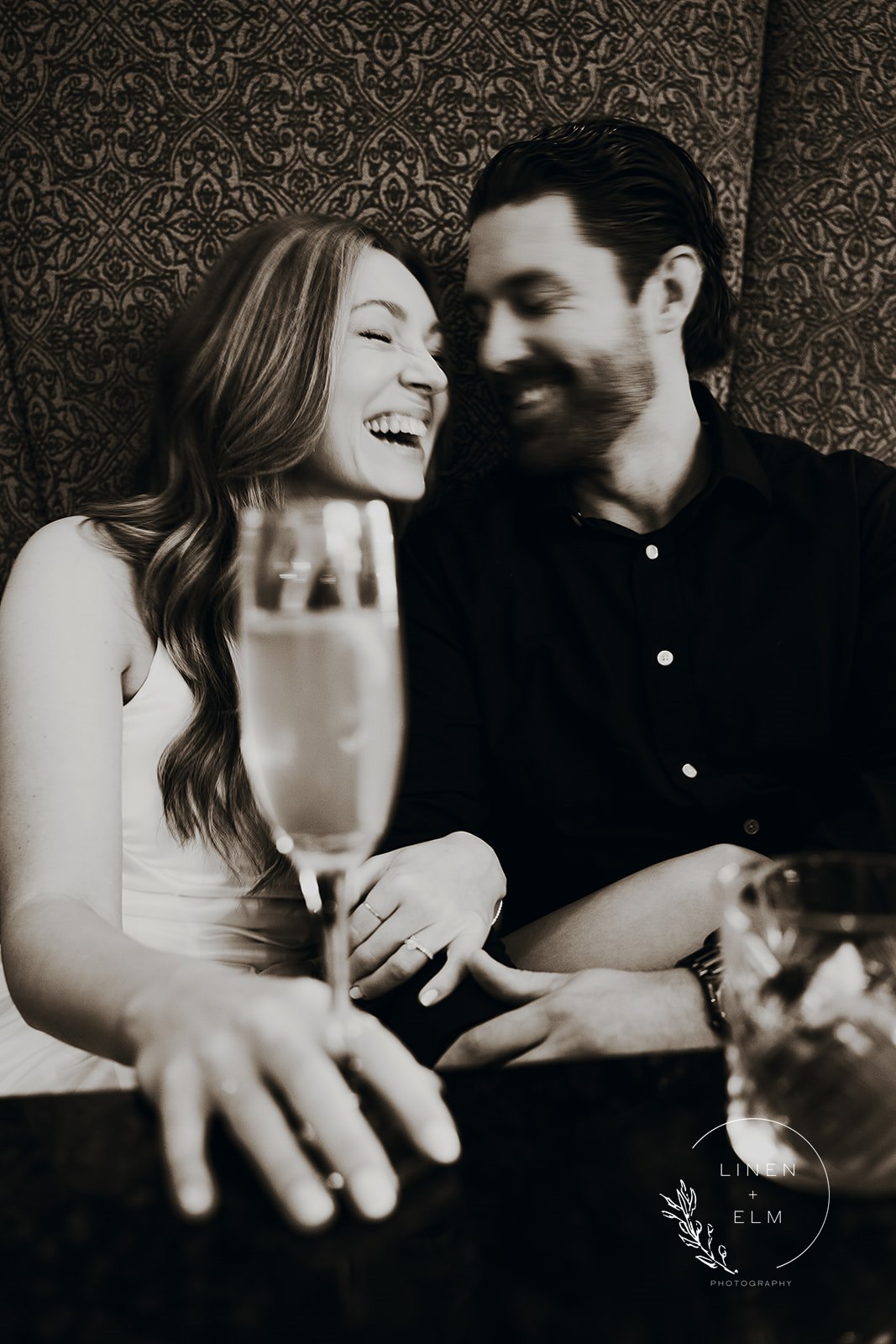Couple laughing over drinks at Hilton Netherland Hotel Cincinnati engagement photography