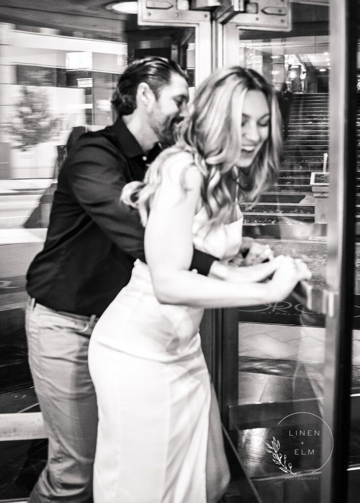 Couple having fun in revolving door at Hilton Netherland Hotel Cincinnati Engagement Photographer