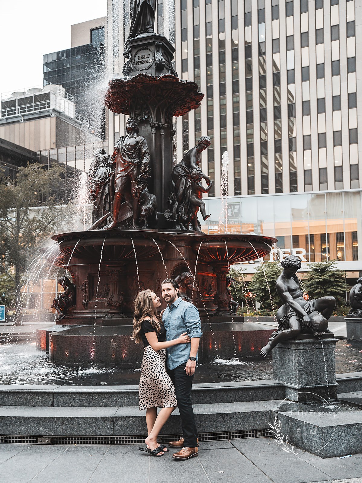 Engaged couple posing in front of Fountain Square Cincinnati